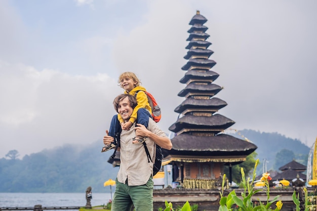 Pai e filho no fundo do templo hindu puro ulun danu bratan bali cercado por flores em