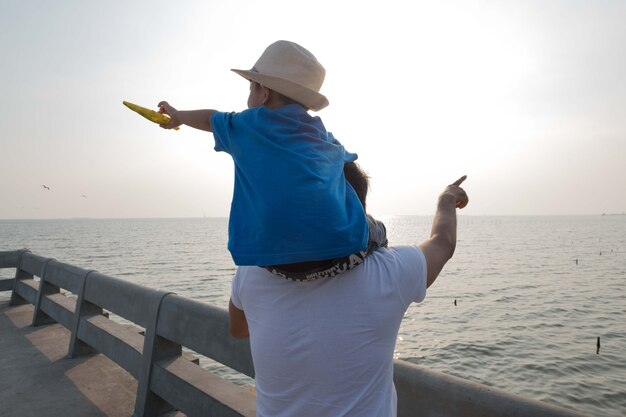 Pai e filho no mar assistindo o por do sol