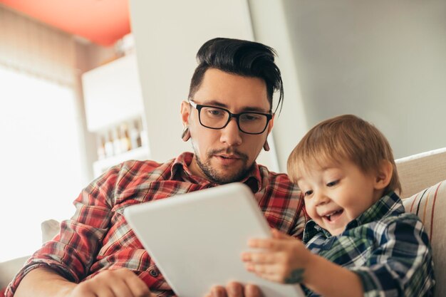 Foto pai e filho no sofá usando tablet