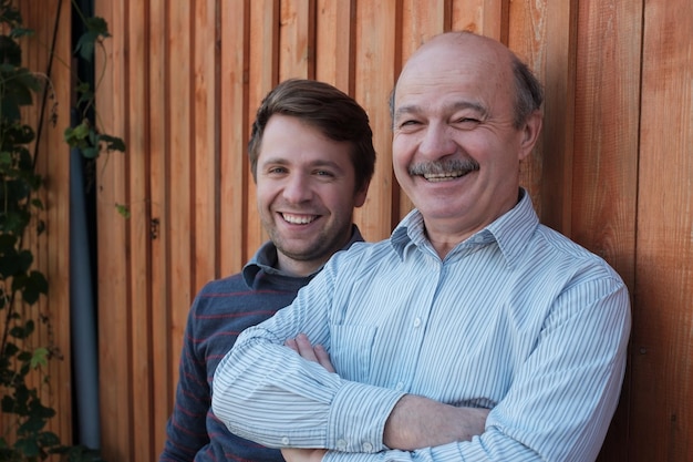 Pai e filho olhando para a câmera em pé ao ar livre