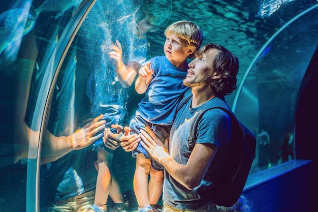 Pai e filho olhando peixes em um aquário de túnel