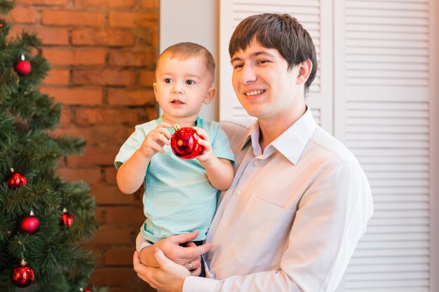 Pai e filho perto de árvore de Natal na sala