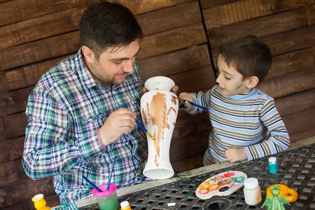 Pai e filho pintam um vaso