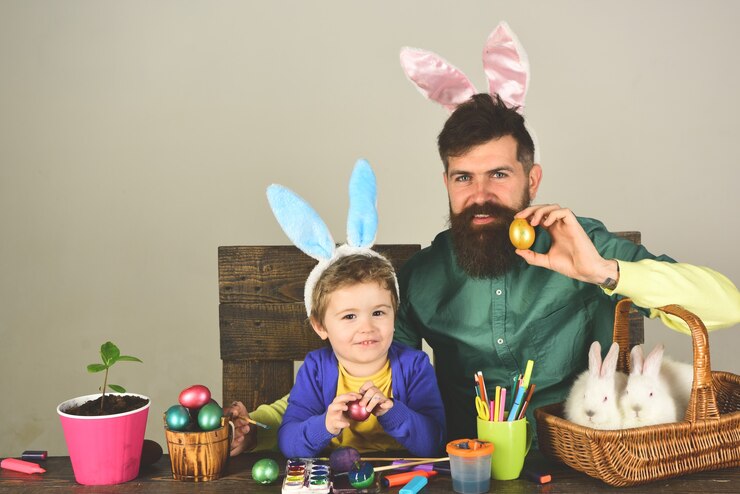 Foto pai e filho pintando ovos de páscoa. família de coelho com orelhas de coelho. menino bonito criança vestindo no dia de páscoa.