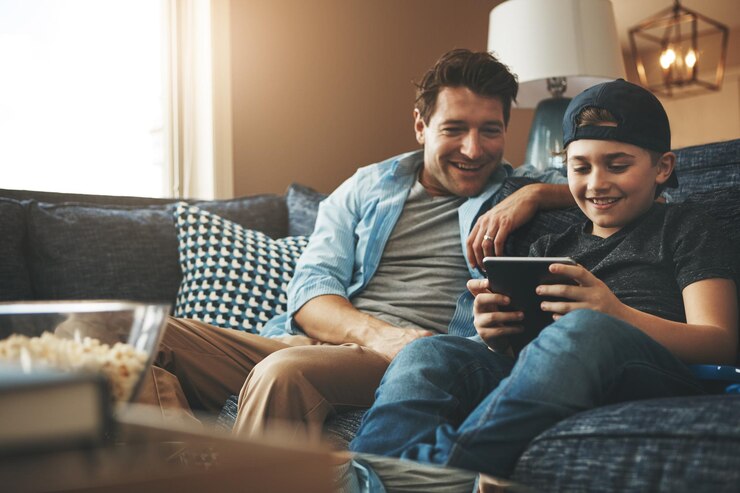 Foto pai e filho relaxam no sofá com tablet para serviço de streaming online filmes ou videogames em férias homem de família excitado ou pai com criança na sala de estar com tecnologia digital para e-aprendizagem em casa