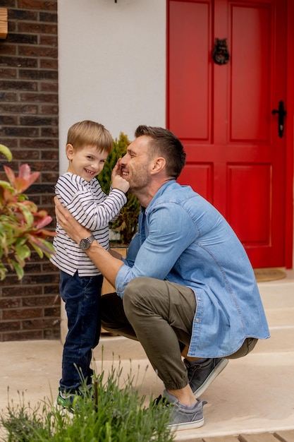 Pai e filho se divertem na frente da porta de casa