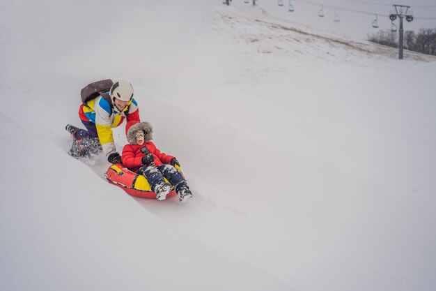 Pai e filho se divertem na tubulação no inverno Diversão de inverno para toda a família