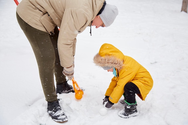 Pai e filho se divertindo juntos em família Férias de inverno Criança feliz se divertindo na neve na cidade Diversão de inverno lá fora