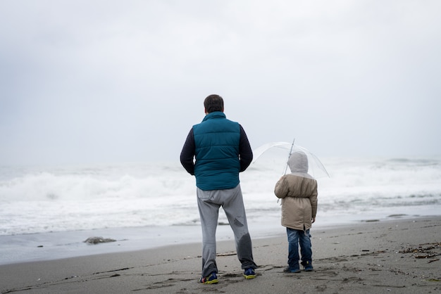 Pai e filho se divertindo na praia de inverno