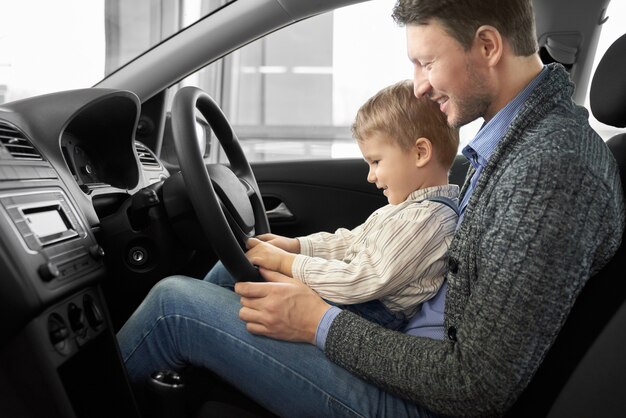 Pai e filho sentado no banco do motorista em automóvel novo.