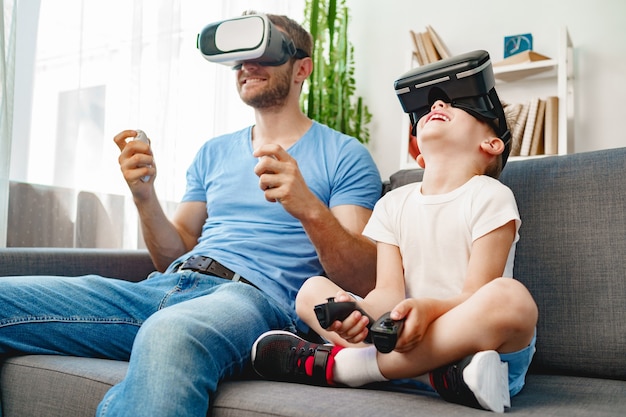 Pai e filho sentados no sofá brincando com óculos de realidade virtual