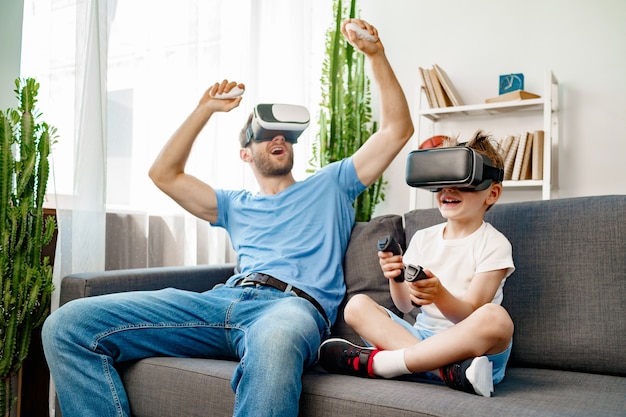 Pai e filho sentados no sofá jogando com óculos de realidade virtual