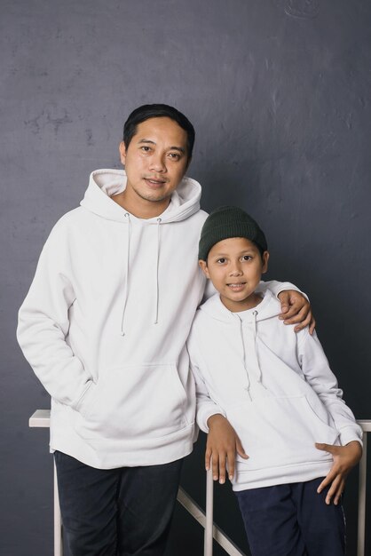 Pai e filho sorrindo e juntos vestindo capuz branco para vestuário simulado isolado em g