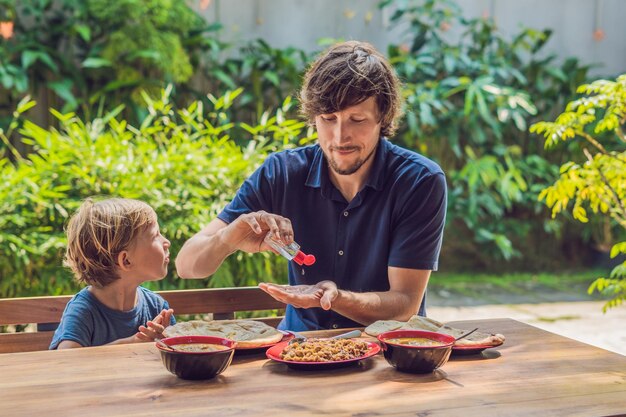 Pai e filho usando gel desinfetante para as mãos antes de comerem em um café