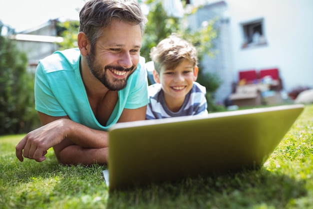 Pai e filho usando laptop no jardim