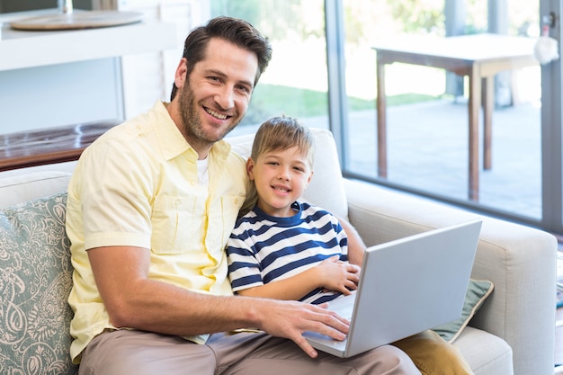 Pai e filho usando laptop no sofá