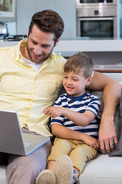 Pai e filho usando laptop no sofá