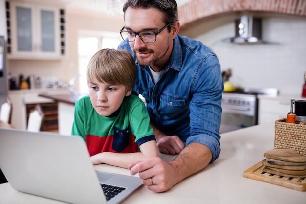 Pai e filho usando o laptop na cozinha