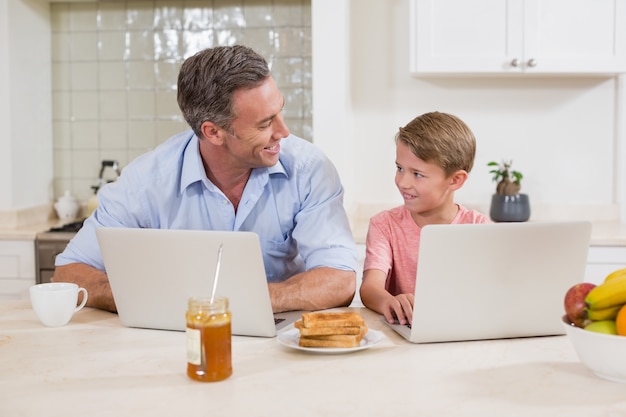 Pai e filho usando o laptop na cozinha