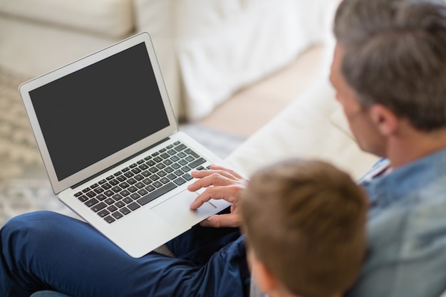 Pai e filho usando o laptop na sala de estar