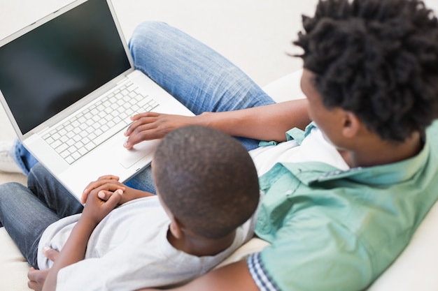 Pai e filho, usando o laptop no sofá