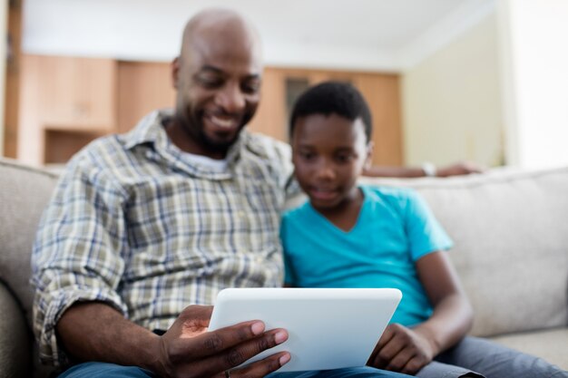 Pai e filho usando tablet digital na sala de estar