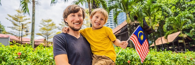 Pai e filho viajantes na malásia com bandeira da malásia comemorando o dia da independência da malásia