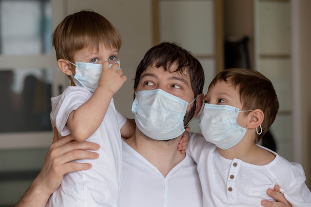 Pai e filhos com máscaras médicas em casa. Imagem com foco seletivo. Foto de alta qualidade