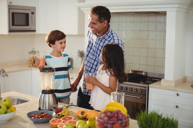 Pai e filhos segurando copo de batido