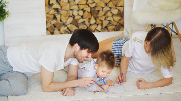 Pai e mãe ajudando seu filho a desenhar na sala de estar