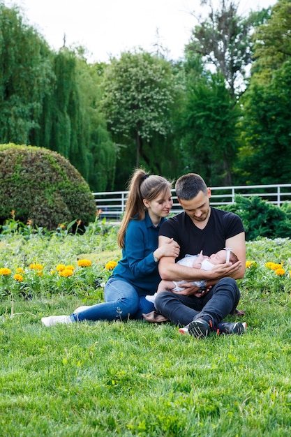 Pai e mãe amorosos com seu bebê recém-nascido nos braços. Linda família com um lindo filho recém-nascido dormindo na natureza ao ar livre. Primeira semana de vida do bebê. Pai feliz e família harmoniosa.