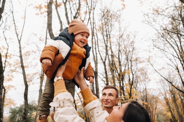 Pai e mãe com filho caminhando no parque outono. Uma família caminha no outono dourado em um parque natural.