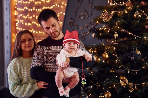 Pai e mãe com seu filho, decorando a árvore juntos na sala.