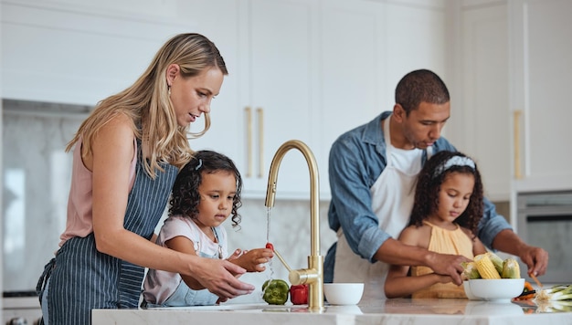 Foto pai e mãe de família com meninas na cozinha lavam legumes e se unem amam mamãe e papai com o desenvolvimento infantil das filhas e adoram preparar salada juntos para o almoço legumes e cozinhar