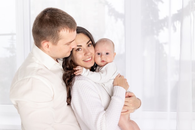 Pai e mãe de família feliz segurando um bebê recém-nascido em casa