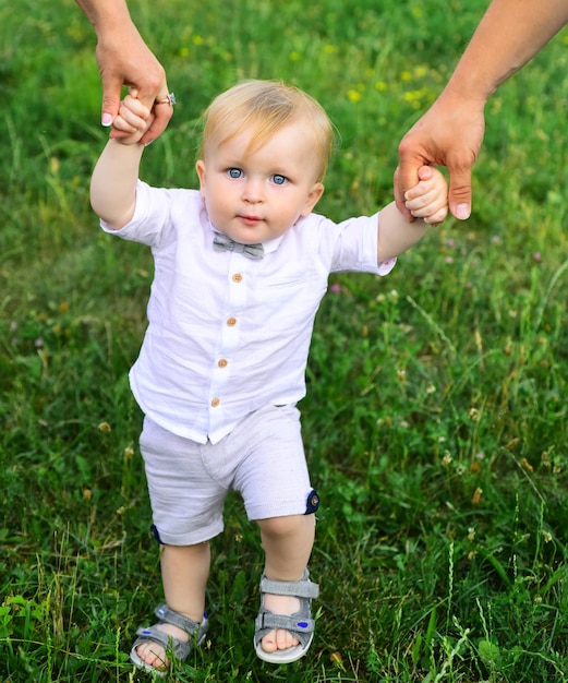 Pai e mãe pais de mãos dadas bebê caminhando juntos na grama no dia de verão Bebê criança enjo