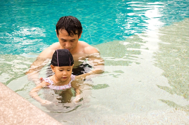 Pai e menina em uma piscina.