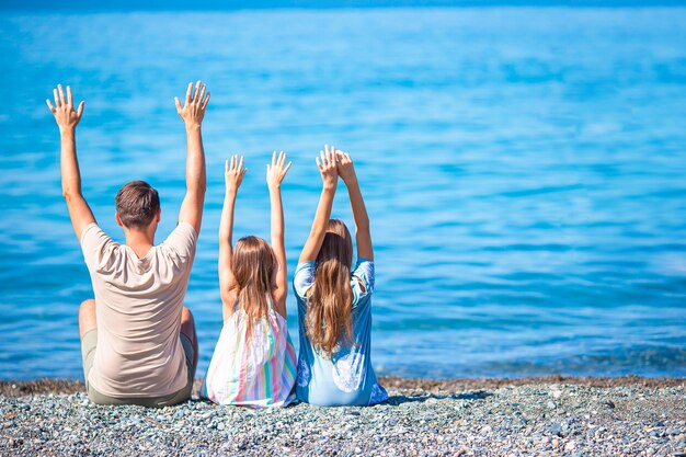 Pai e meninas na praia se divertem nas férias de verão