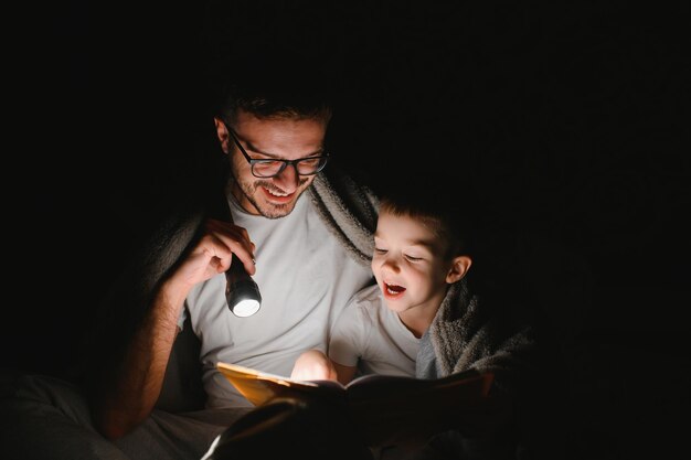 Pai e seu filho lendo história de ninar em casa