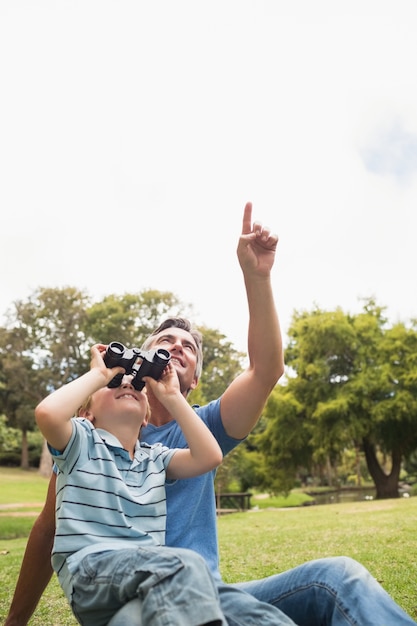 Pai e seu filho usando binocular no parque