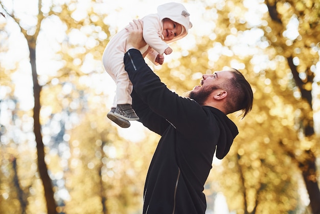 Pai em roupas casuais com seu filho está no belo parque de outono.