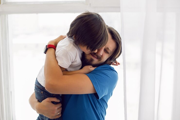Foto pai em uma camisa azul e um filho em uma camiseta branca sentado no peitoral de uma grande janela