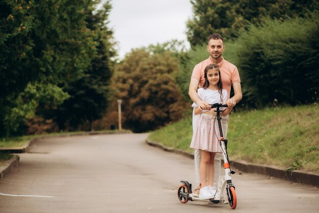 Foto pai ensina filha a andar de scooter elétrico