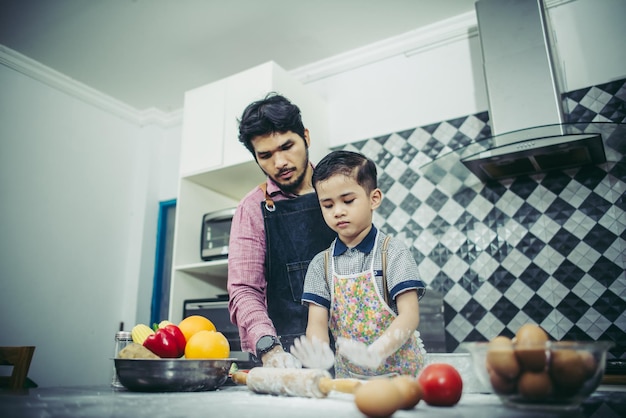 Pai ensina seu filho a cozinhar na cozinha em casa conceito de família