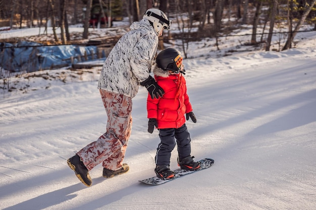 Pai ensina snowboard ao filho Atividades para crianças no inverno Esporte infantil de inverno Estilo de vida