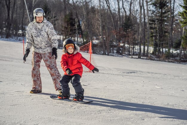 Pai ensina snowboard ao filho Atividades para crianças no inverno Esporte infantil de inverno Estilo de vida