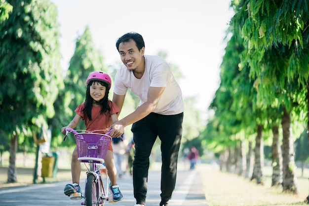 Pai ensinando filha a andar de bicicleta no parque