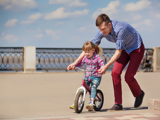 Pai ensinando filha a andar de bicicleta