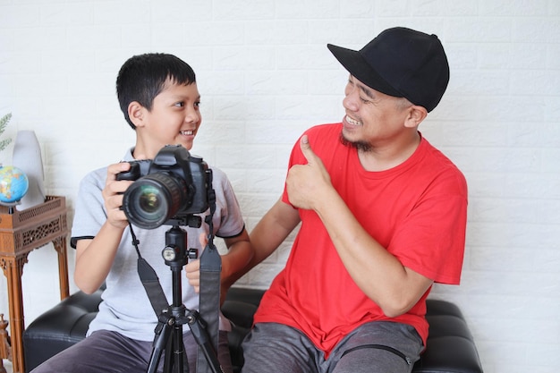 Pai ensinando filho bonitinho a usar câmera digital para fotografia