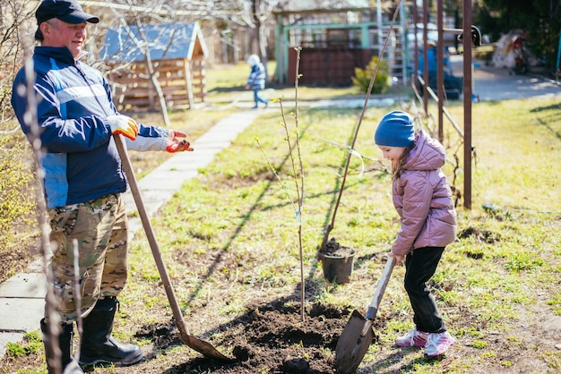 Pai ensinando sua filha a plantar uma nova árvore na primavera